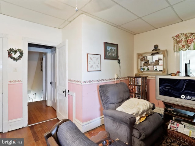 living area featuring wood finished floors and a paneled ceiling