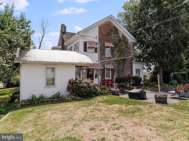 back of property featuring a patio area, metal roof, and a lawn