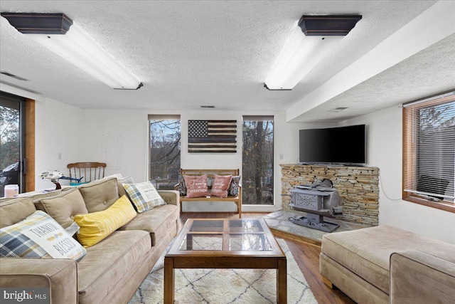 living room with a textured ceiling, wood finished floors, and a wood stove