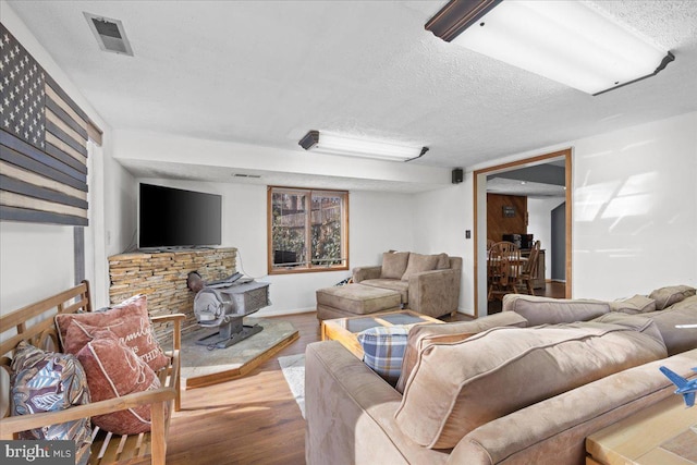 living room with a textured ceiling, wood finished floors, and visible vents