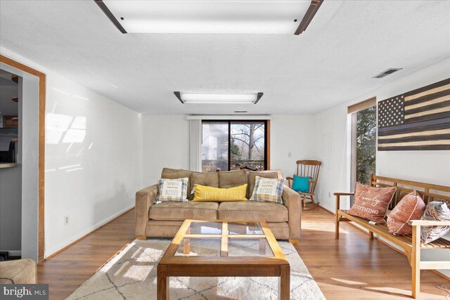 living room with a textured ceiling, a wealth of natural light, wood finished floors, and visible vents