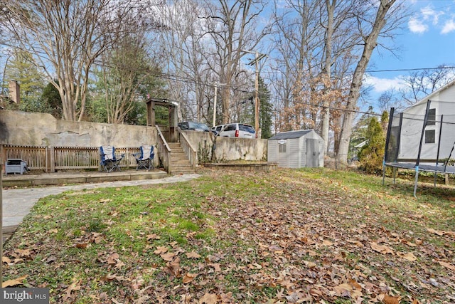 view of yard with a shed, a trampoline, an outdoor structure, and fence