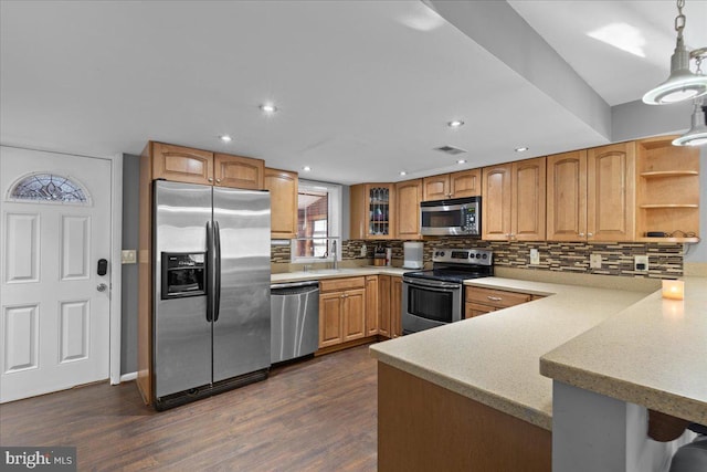 kitchen featuring tasteful backsplash, dark wood-style floors, a peninsula, stainless steel appliances, and light countertops