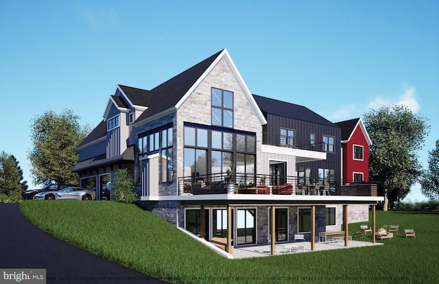 back of house with a balcony, stone siding, a yard, board and batten siding, and a patio area