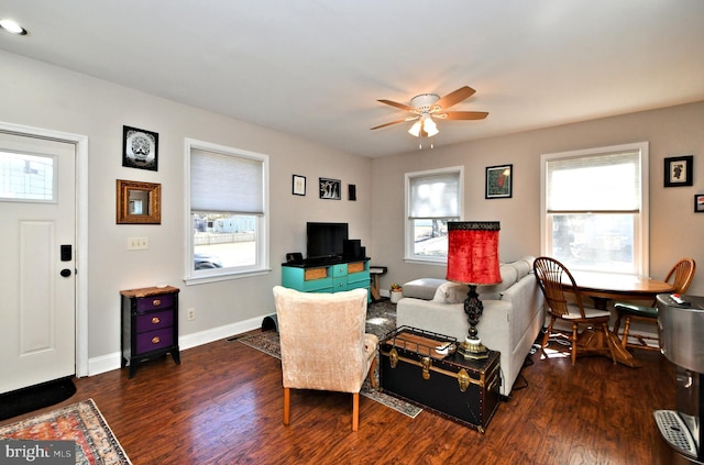 living room with a healthy amount of sunlight, a ceiling fan, baseboards, and dark wood-type flooring