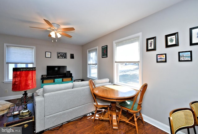 living room with ceiling fan, baseboards, and dark wood finished floors