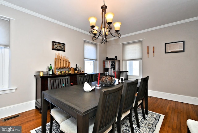 dining room featuring hardwood / wood-style flooring, visible vents, and crown molding