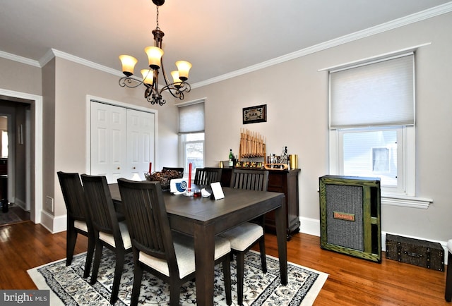 dining space featuring a chandelier, ornamental molding, baseboards, and wood finished floors