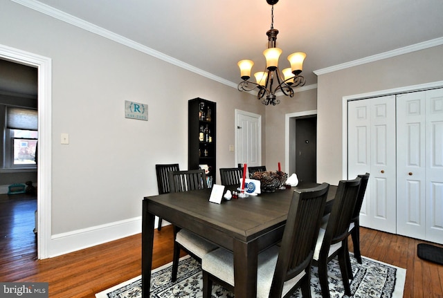 dining space featuring hardwood / wood-style flooring, baseboards, a notable chandelier, and ornamental molding