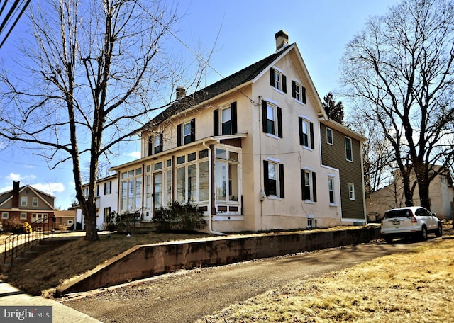 view of front of house featuring a chimney and stucco siding