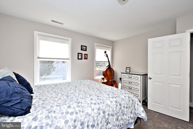 bedroom featuring dark colored carpet and visible vents