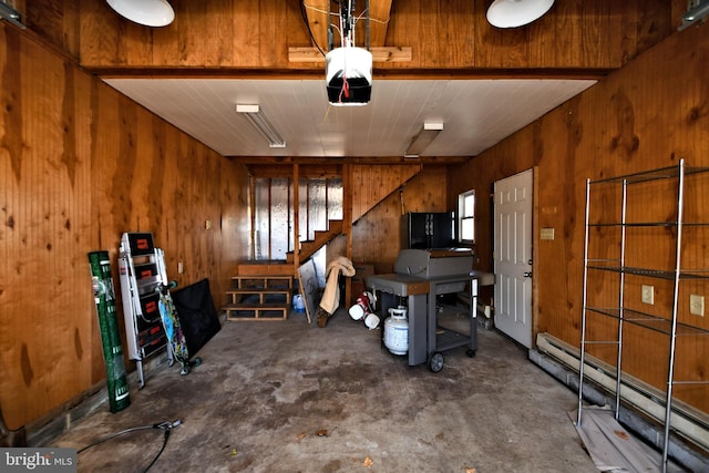 garage with a garage door opener, a baseboard heating unit, and wooden walls