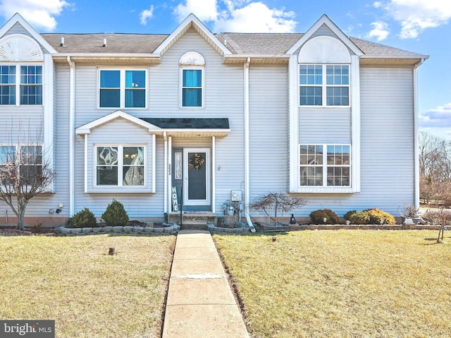 view of front of house featuring a shingled roof and a front lawn