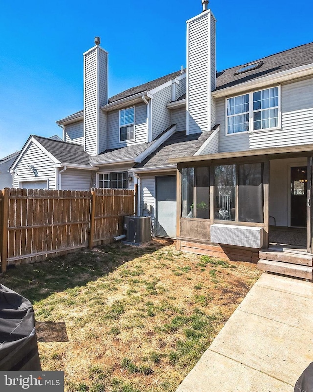 back of property featuring fence, a yard, a sunroom, a chimney, and central air condition unit