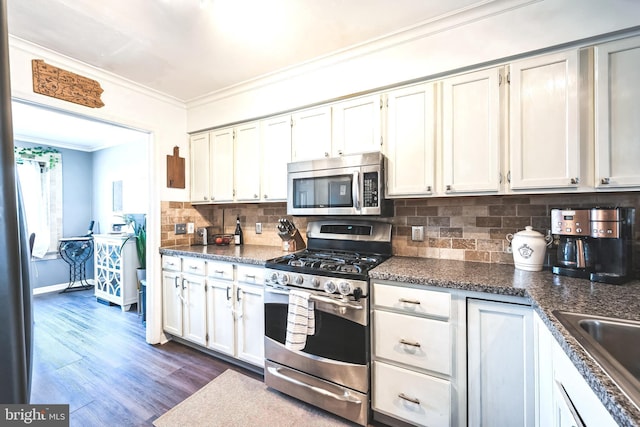 kitchen featuring ornamental molding, dark countertops, tasteful backsplash, appliances with stainless steel finishes, and dark wood-style flooring