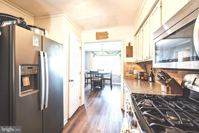 kitchen with dark countertops, backsplash, ornamental molding, appliances with stainless steel finishes, and dark wood-style flooring