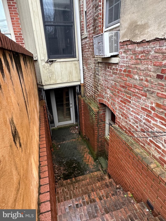 doorway to property featuring fence, cooling unit, and brick siding