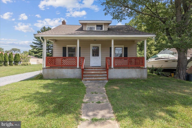 bungalow-style house with a porch, a front yard, a shingled roof, and a chimney