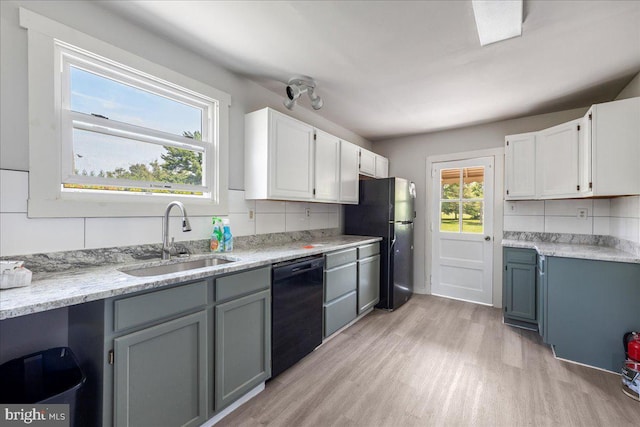 kitchen with light wood-style flooring, decorative backsplash, white cabinets, a sink, and black appliances