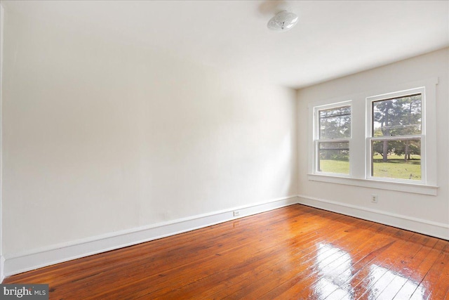 spare room with hardwood / wood-style floors and baseboards