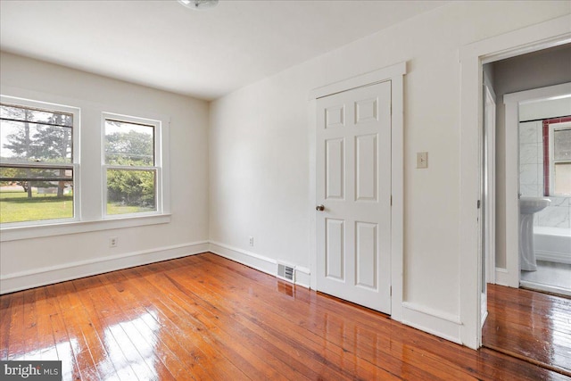 unfurnished bedroom with visible vents, baseboards, and hardwood / wood-style floors