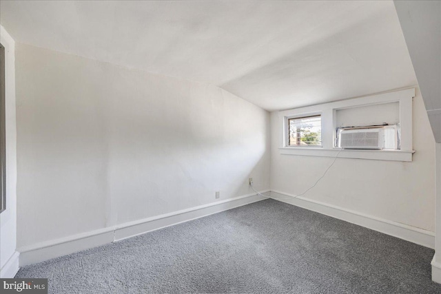 empty room with carpet, cooling unit, vaulted ceiling, and baseboards