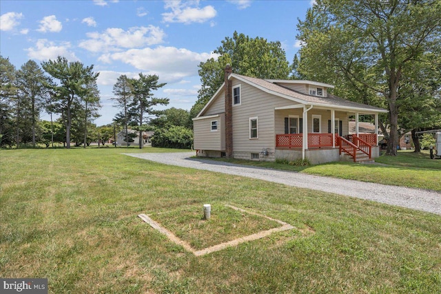 view of front facade featuring driveway, covered porch, and a front lawn