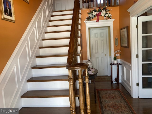 stairway with wainscoting and wood finished floors