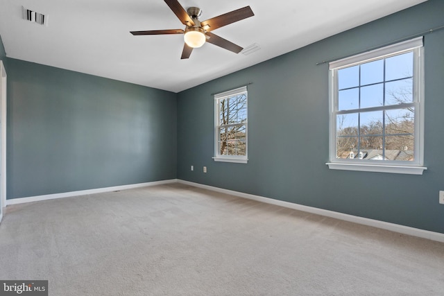 carpeted empty room with visible vents, baseboards, and a ceiling fan