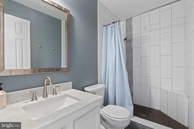 full bathroom featuring vanity, toilet, and tiled shower