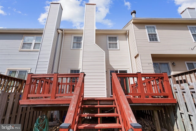 back of property featuring a wooden deck, a chimney, and stairway