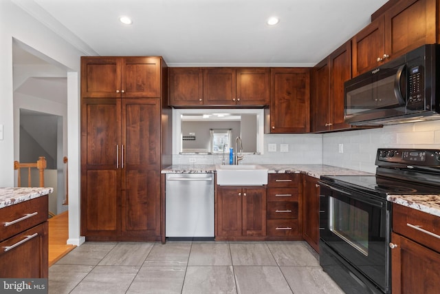 kitchen with tasteful backsplash, light stone counters, recessed lighting, black appliances, and a sink