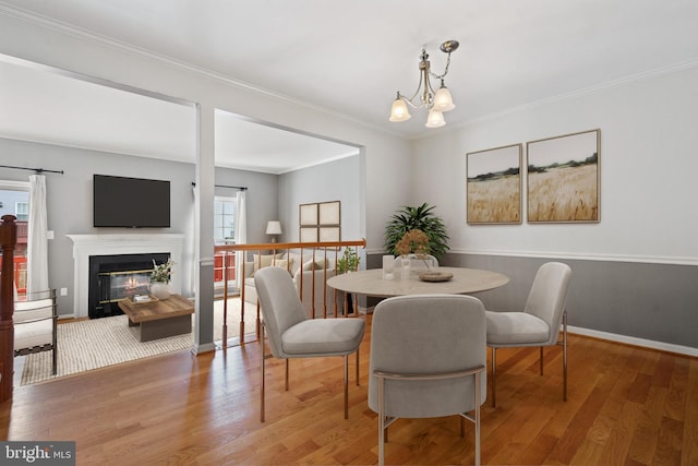 dining space with a chandelier, crown molding, and wood finished floors