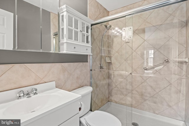 bathroom with vanity, tile walls, toilet, and a stall shower