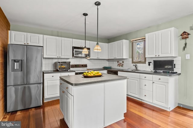 kitchen featuring stainless steel appliances, dark countertops, wood finished floors, and white cabinets