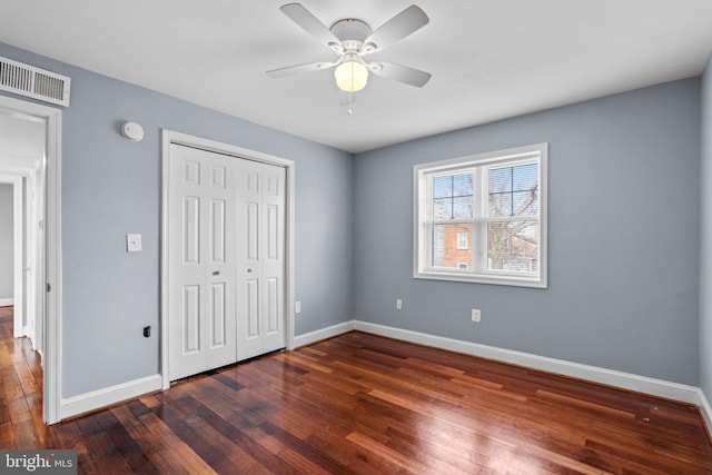 unfurnished bedroom featuring wood-type flooring, a closet, visible vents, and baseboards