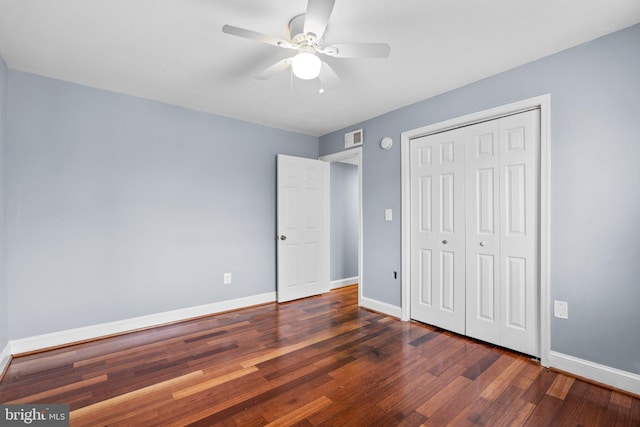 unfurnished bedroom featuring a closet, visible vents, baseboards, and wood finished floors