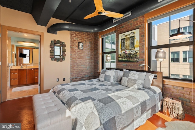 bedroom featuring multiple windows, ensuite bath, and brick wall