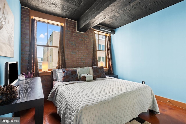 bedroom with multiple windows, brick wall, baseboards, and wood finished floors