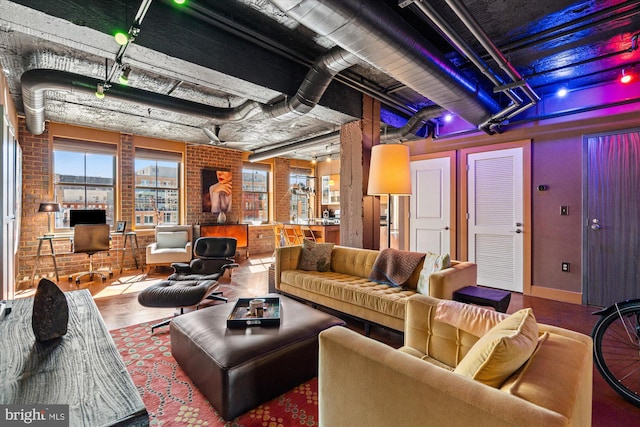 living area with brick wall and wood finished floors