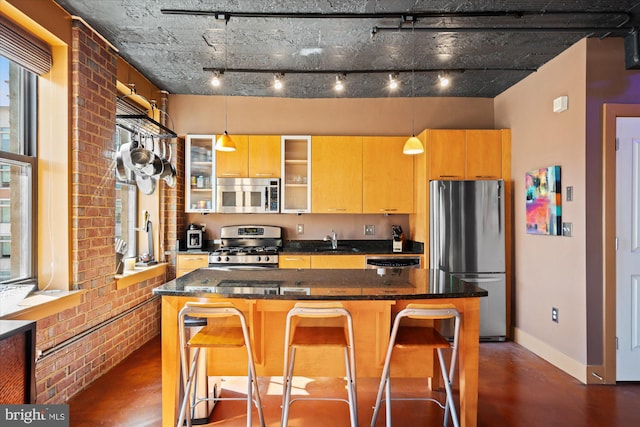 kitchen with a sink, a kitchen breakfast bar, a kitchen island, stainless steel appliances, and brick wall