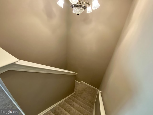 stairway with carpet flooring, a notable chandelier, and baseboards