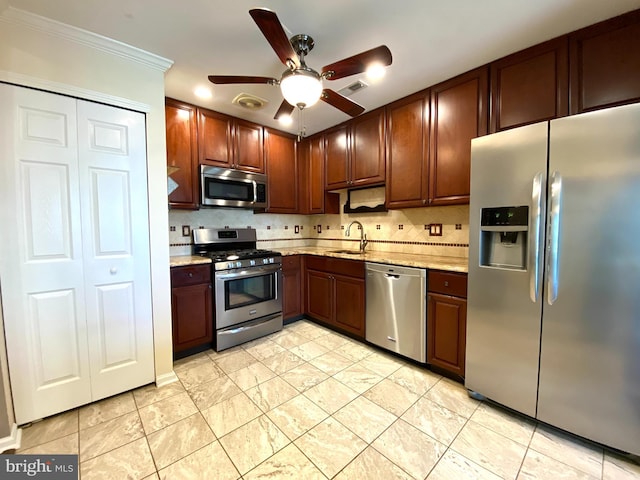 kitchen with light stone counters, stainless steel appliances, decorative backsplash, a ceiling fan, and a sink