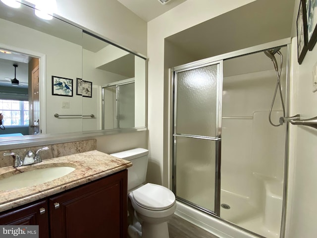 bathroom featuring ceiling fan, a stall shower, vanity, and toilet