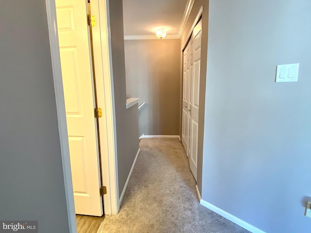 hall with baseboards, crown molding, and light colored carpet