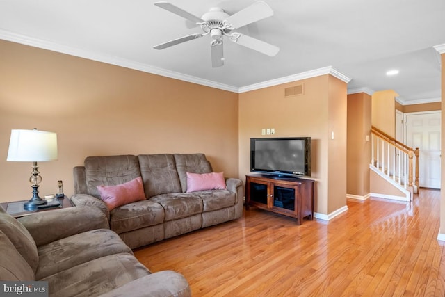 living room with baseboards, visible vents, light wood-style flooring, stairs, and crown molding