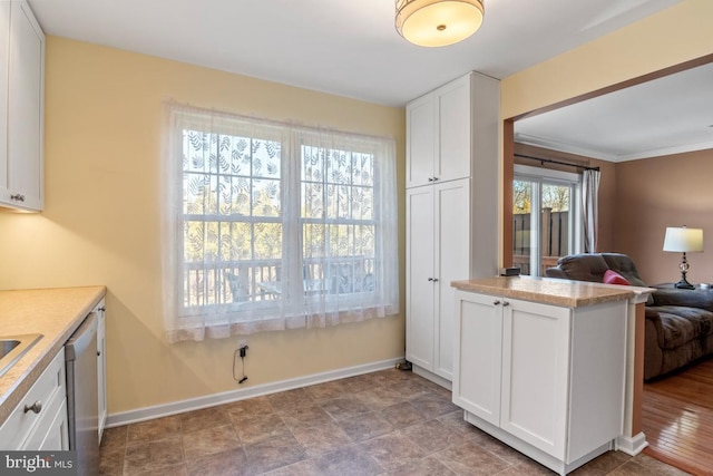 kitchen with open floor plan, white cabinetry, light countertops, and baseboards