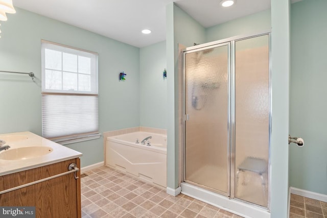 full bath with baseboards, double vanity, a sink, a shower stall, and a garden tub