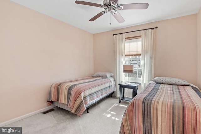 bedroom featuring visible vents, baseboards, light colored carpet, and a ceiling fan