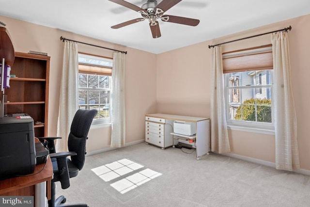 carpeted home office with plenty of natural light, a ceiling fan, and baseboards